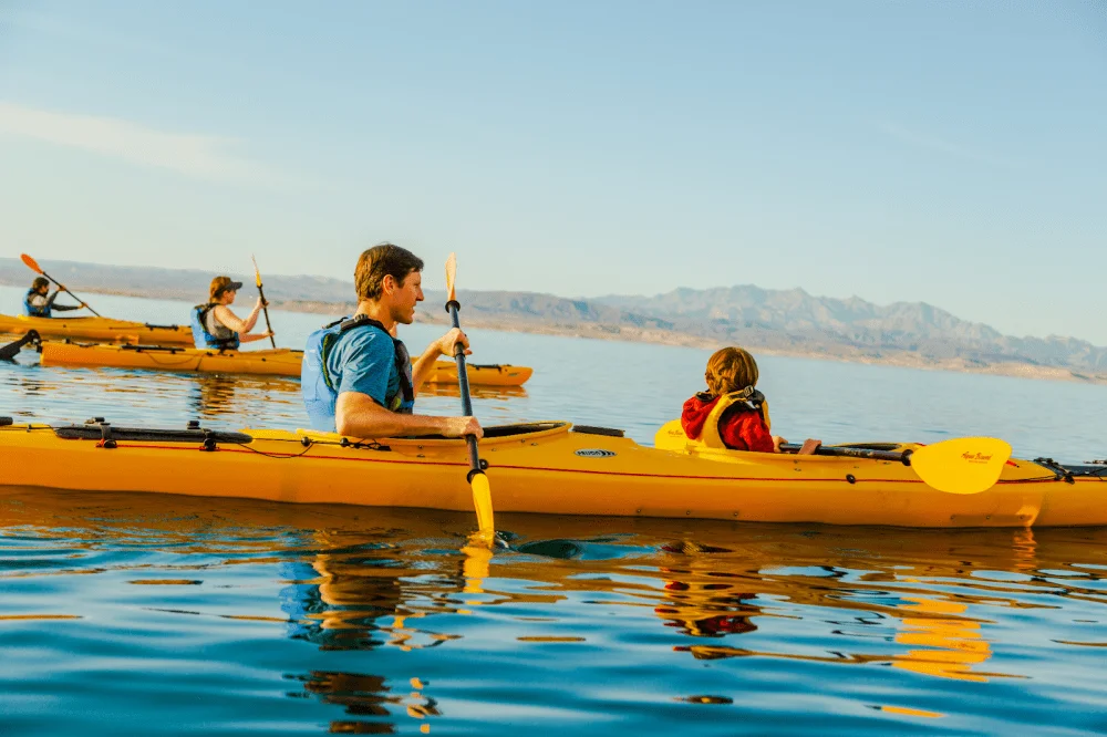 Kayakers exploring Lake Mead beneath desert cliffs