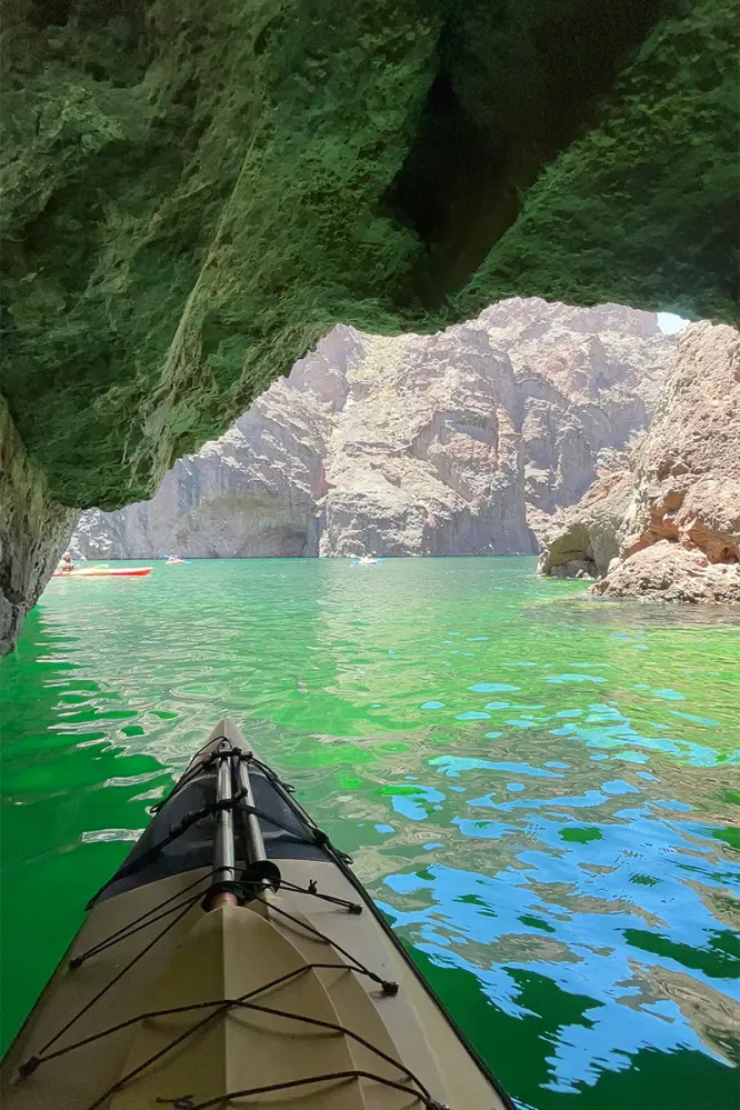 View from a kayak in Emerald Cave looking toward green water and rocky cliffs