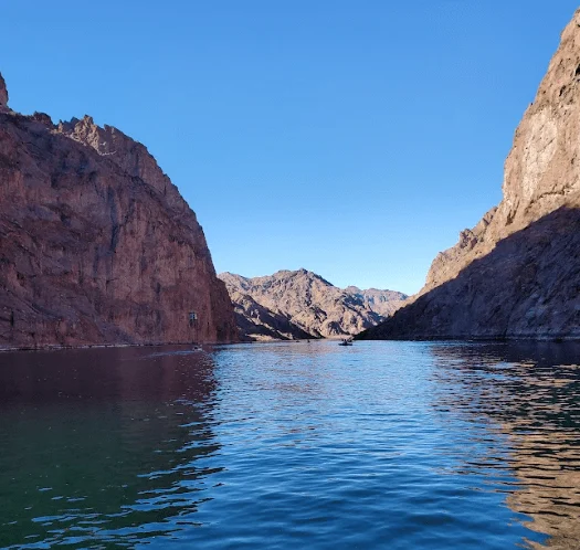 Lake surrounded by rocky cliffs under a clear blue sky.