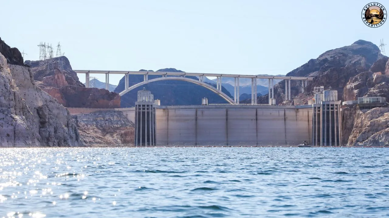 Kayakers on calm water beneath the rocky desert landscape near Hoover Dam.