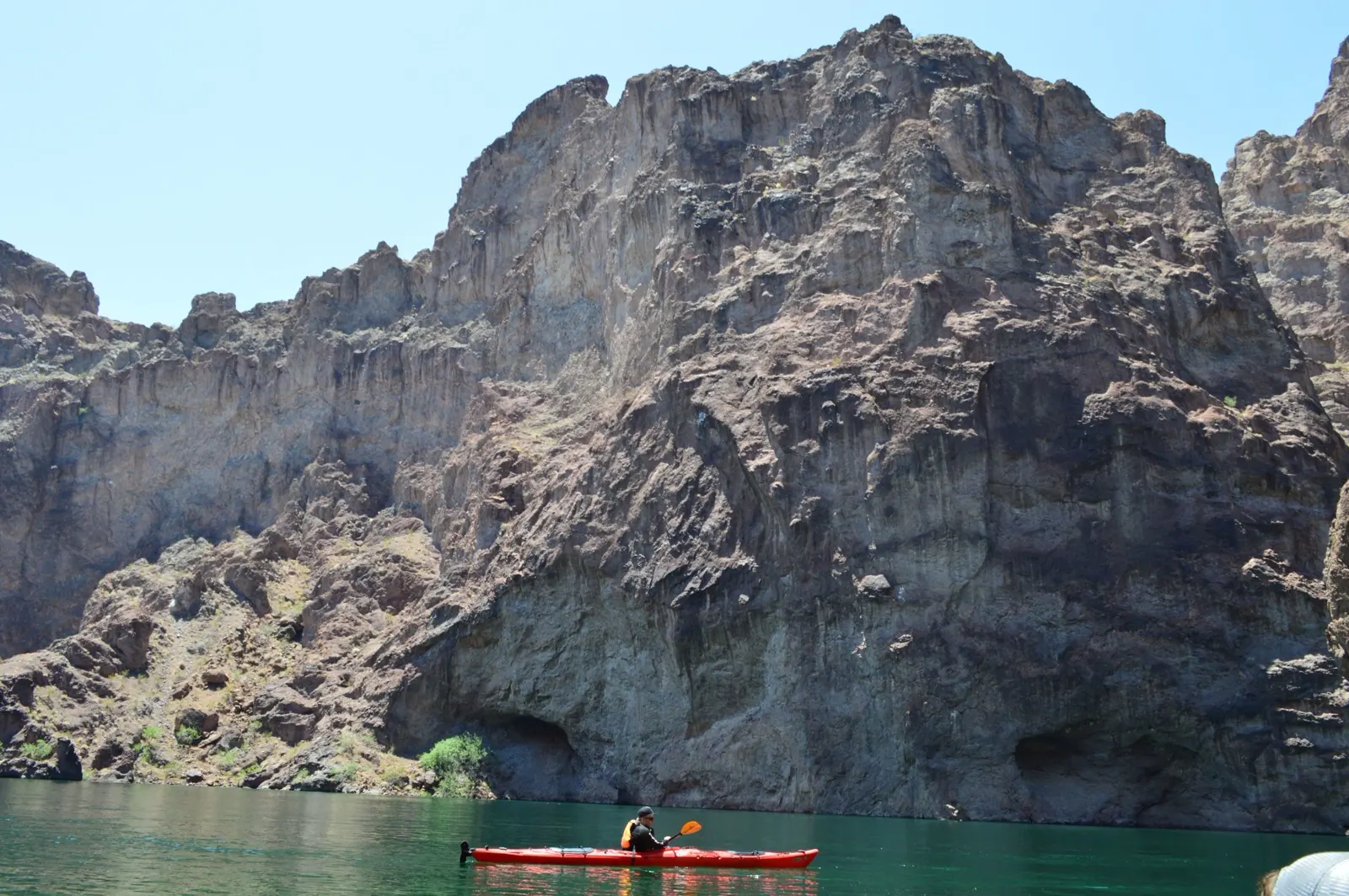 A kayaker paddles a red touring kayak on the Colorado River near Las Vegas.