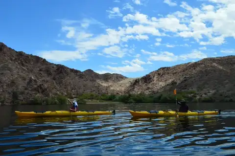Two yellow kayaks paddling side by side on the Colorado River