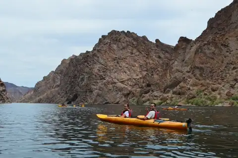 Couple paddling a tandem kayak through the towering walls of Black Canyon