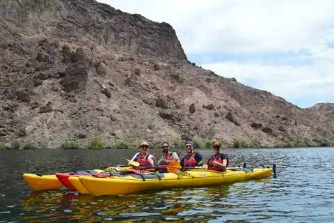 Group of four paddlers smiling in a multi-person kayak on the Colorado River