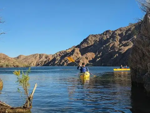 Paddler kayaking on the Colorado River with the group behind on a calm afternoon