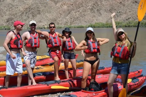 A team posing together beside kayaks on the river