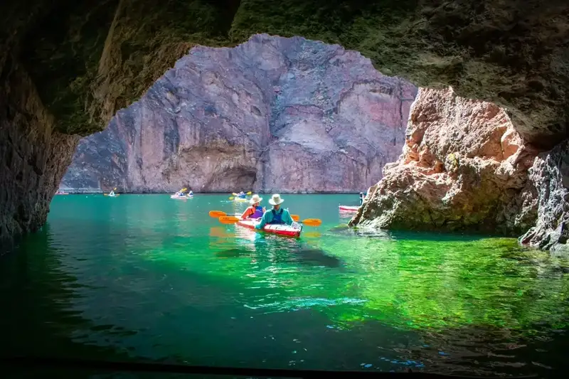 Kayakers paddling into the glowing emerald waters of Emerald Cave