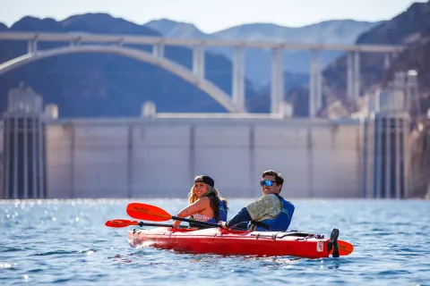 Kayakers paddling with the Hoover Dam bypass bridge overhead