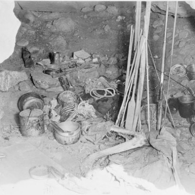 Campsite scene with pots, ropes, and equipment in a rocky cave.