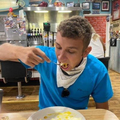 Person in blue shirt eating at a diner with a retro interior.