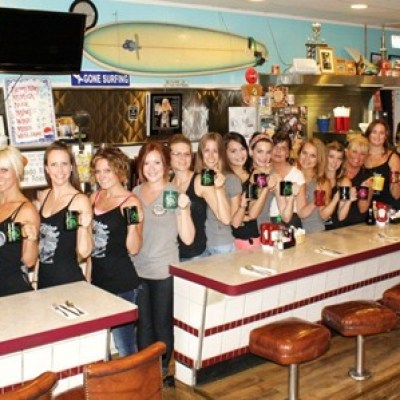Group of people holding coffee mugs behind a diner counter.