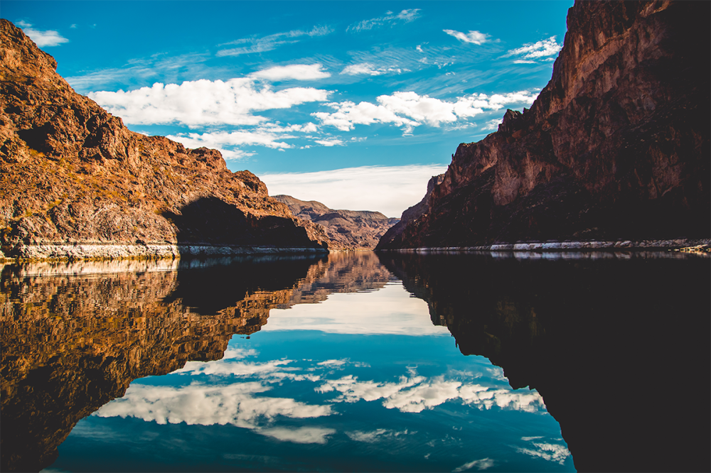 Canyon lake view with clear sky and rocky cliffs reflecting on water.