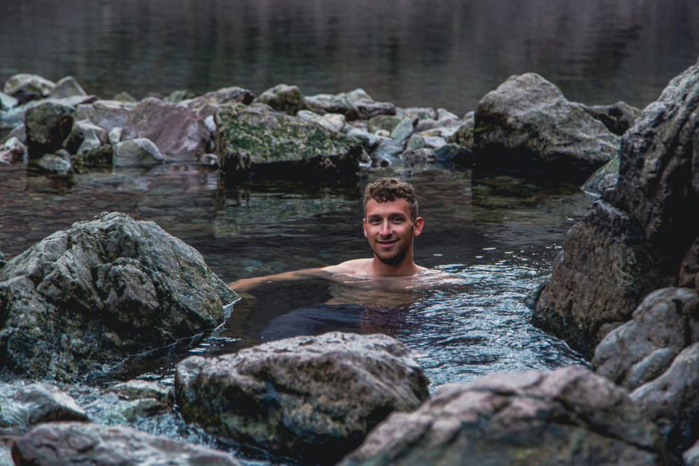 Man swimming in a rocky river with water and rocks surrounding him.