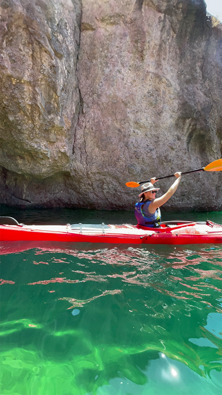 A kayaker paddling the emerald green waters of the cave surrounded by the Grand Canyon walls.