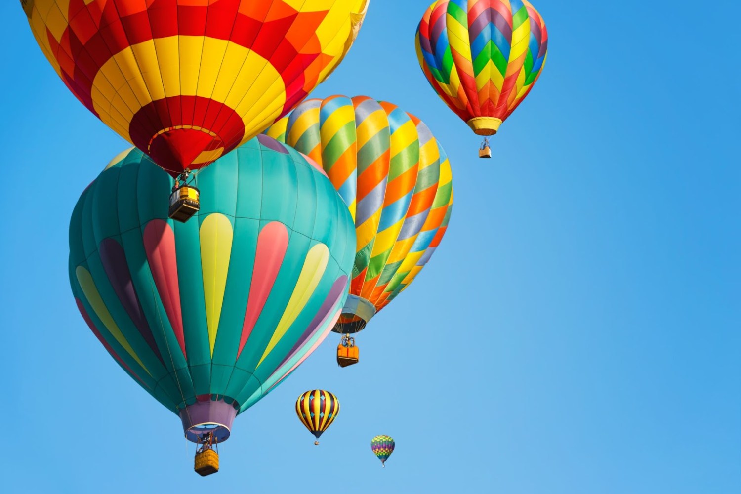 Colorful hot air balloons floating in a clear blue sky.