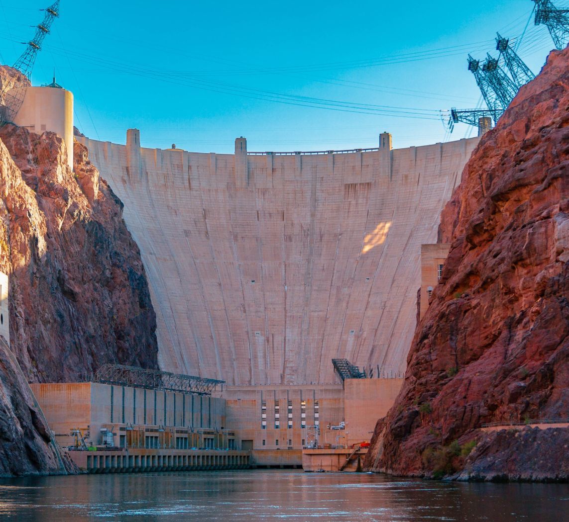 Large dam between rocky cliffs under a clear blue sky.