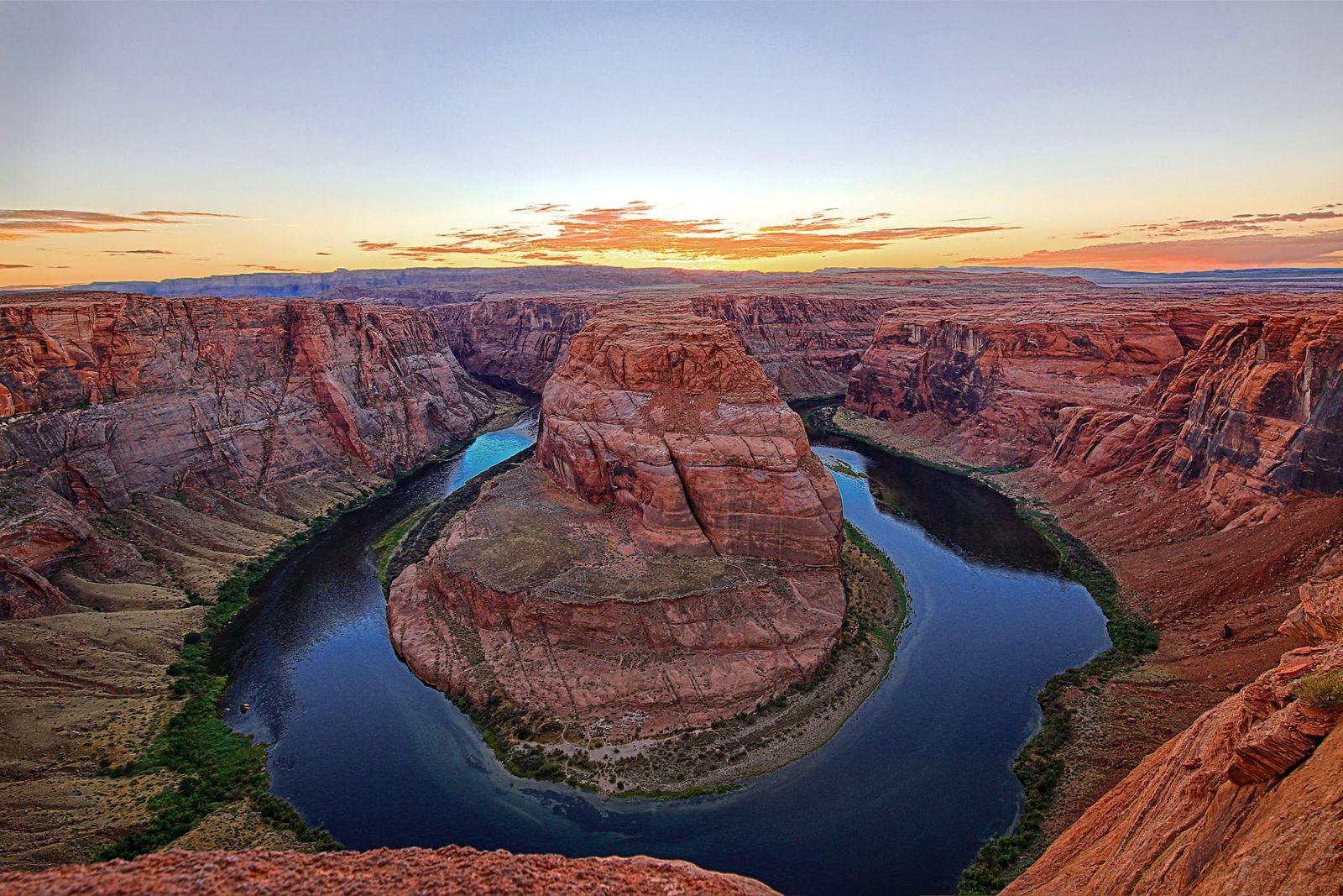 Scenic view of Horseshoe Bend at sunset with a winding river and red rock canyon.