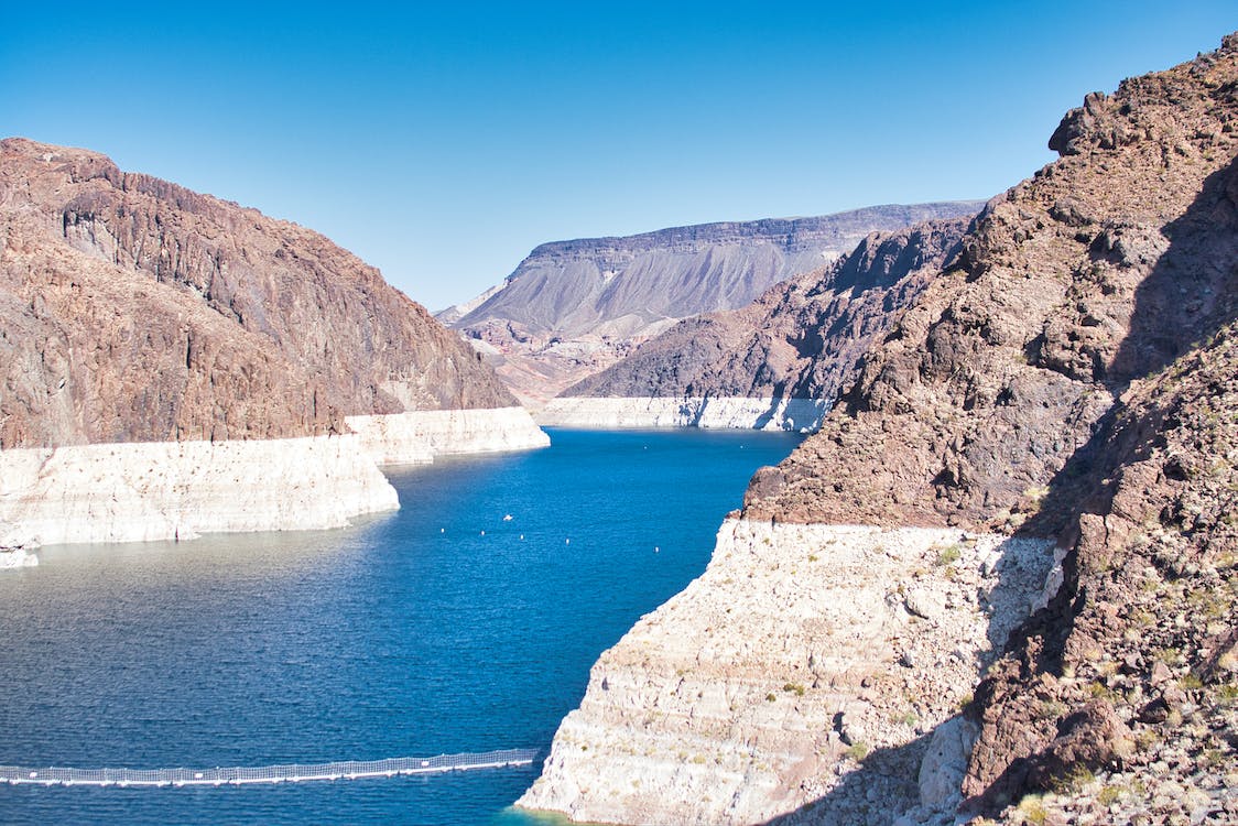 Rocky cliffs and blue water under a clear sky in a canyon landscape.