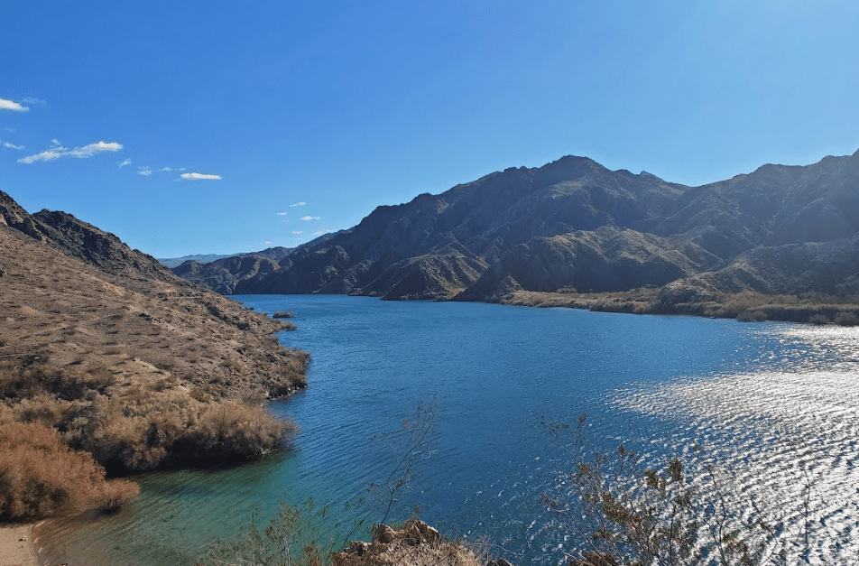 Blue lake surrounded by arid mountains under a clear blue sky.