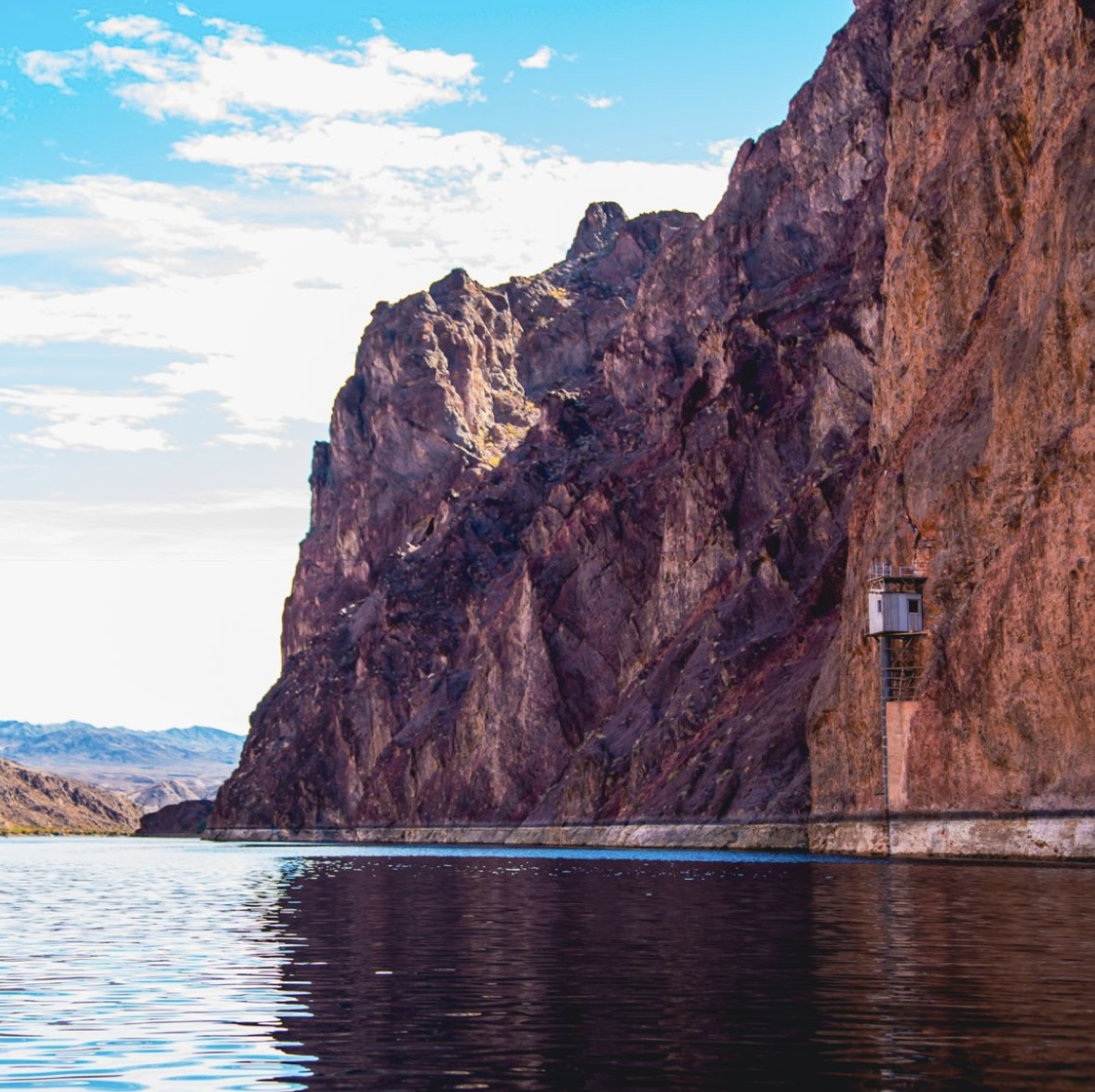Rocky cliff over water with a small observation box embedded in the cliff.