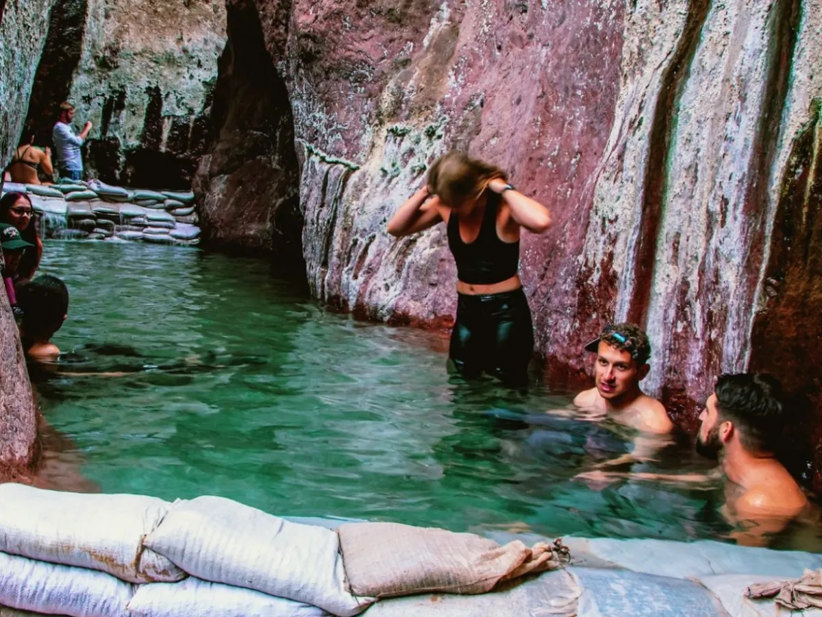 People swimming in a rocky canyon pool with sandbags at the edge.