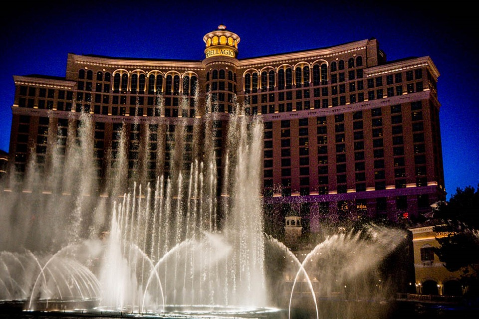 Illuminated hotel with fountain jets shooting into the night sky.