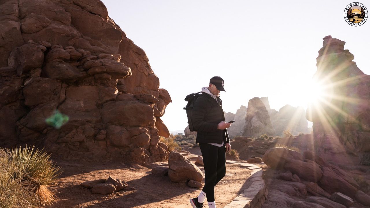 Person hiking in a rocky desert landscape with the sun shining brightly.