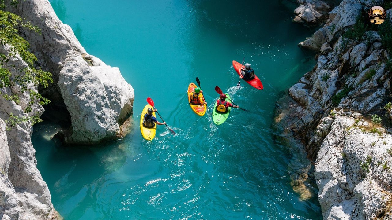 Four kayakers paddle on turquoise water between rocky cliffs.
