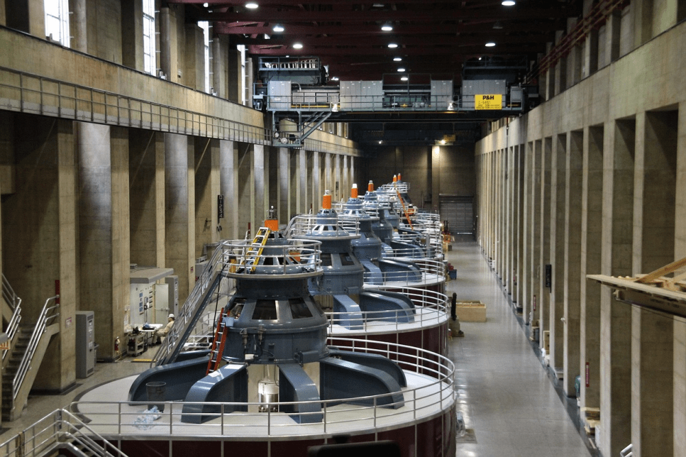 Interior of a hydroelectric power plant with multiple generators in a large hall.