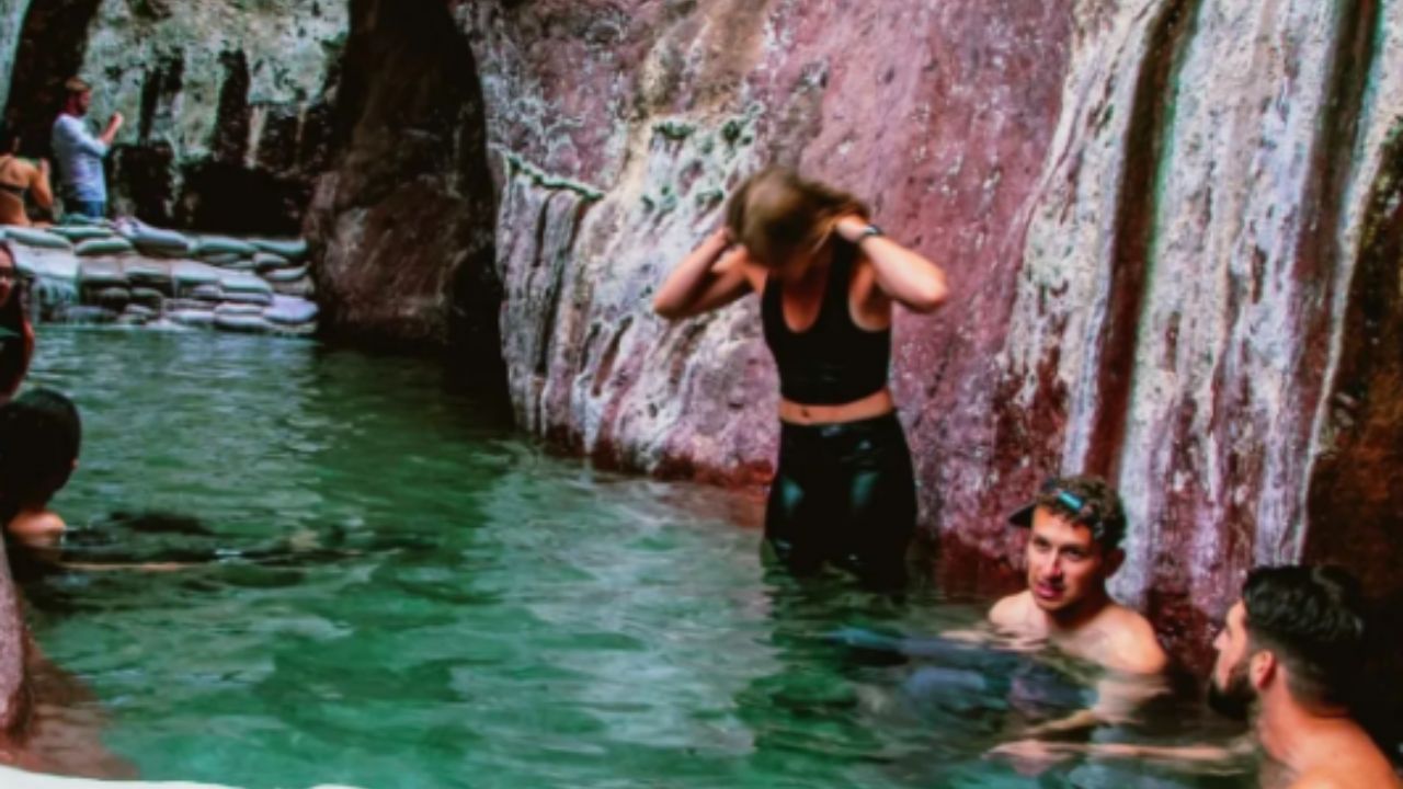 People soaking in a natural rock hot spring pool as part of Evolution Expeditions guided hike tour.