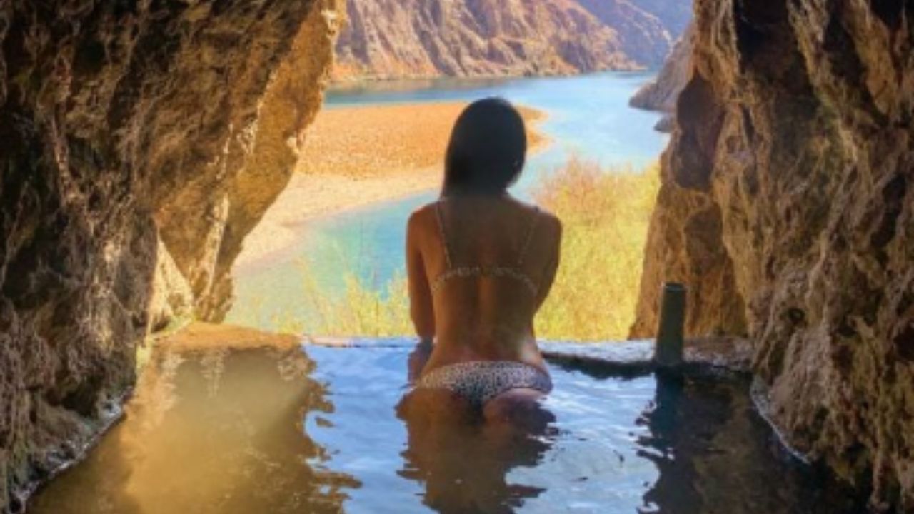 Person sitting in a hot spring pool inside a rocky cave.