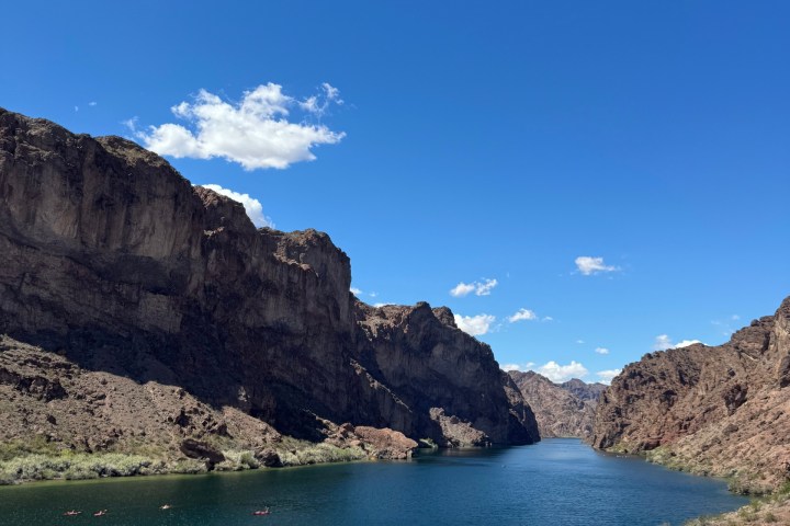 Canyon with blue river under clear sky and sparse clouds.